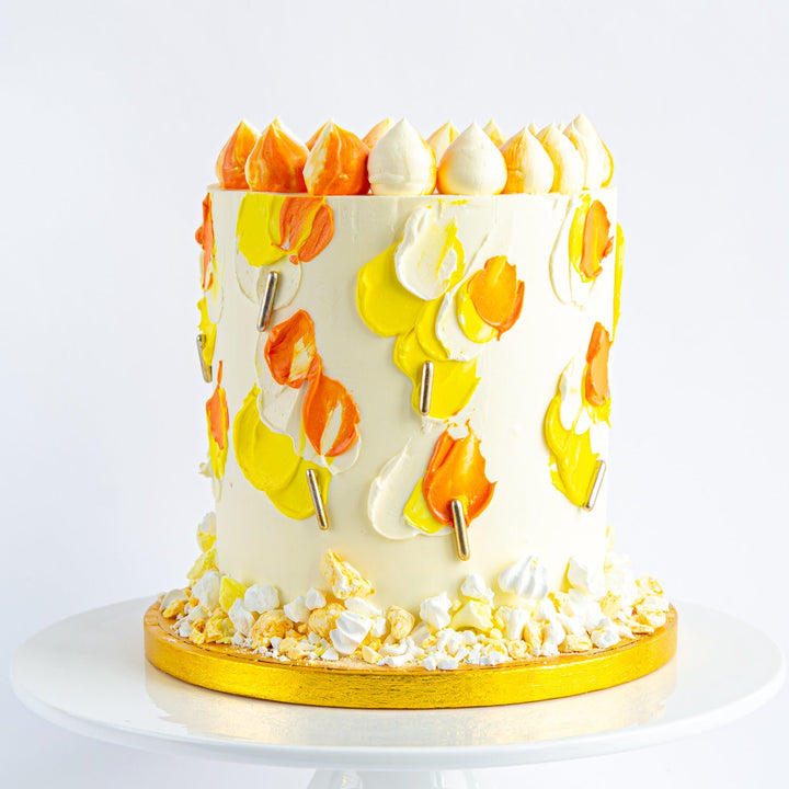 Carrot cake with tangy cream cheese frosting, decorated in vibrant yellows and orange.