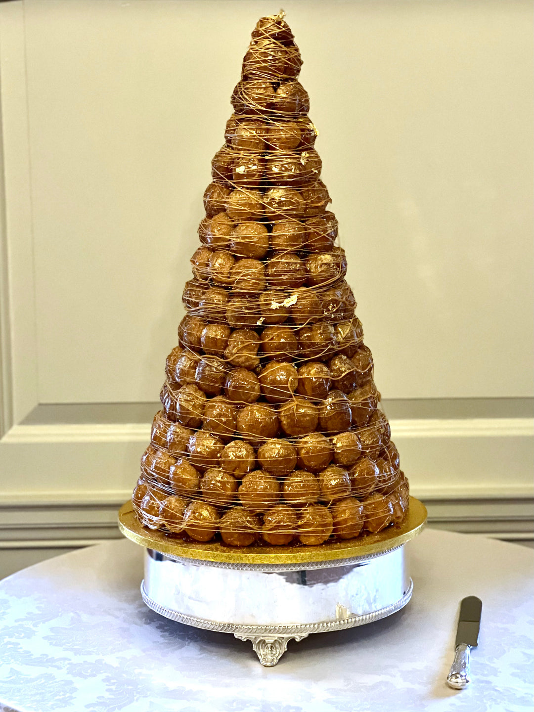 A croquembouche on a stand with a knife