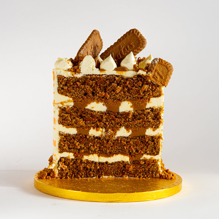 Punk Cake's slice of Biscoff Carrot Cake, with four layers of moist carrot cake sponge, sweet, spicy Biscoff spread and tangy cream cheese frosting. Decorated with Lotus biscuits.