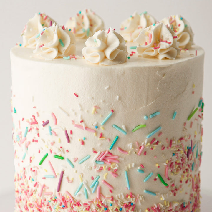 vanilla sponge cake with meringue buttercream, decorated with sprinkles and rosettes