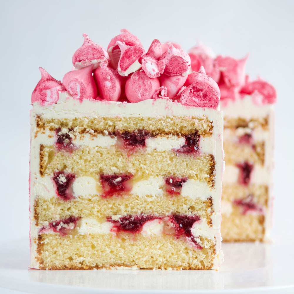 slice of lemon, raspberries and cream layer cake with pink meringue  decoration