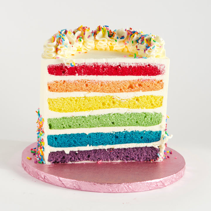 Six layers of vanilla rainbow cake, in vibrant red, orange, yellow, green, blue and purple. Filled with velvety Swiss meringue buttercream and covered in rainbow sprinkles. Finished with buttercream rosettes and sprinkles. 