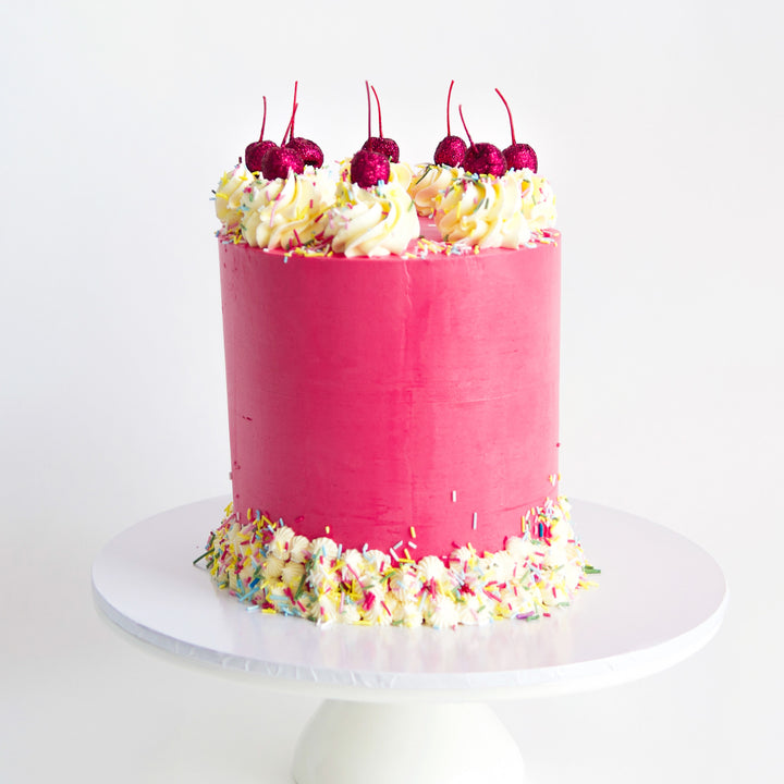strawberry milkshake, red velvet and vanilla cake in deep pink with sprinkles, buttercream rosettes and glitter cherries