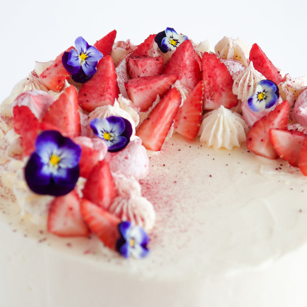 cake decoration details of purple flowers, strawberries and buttercream rosettes