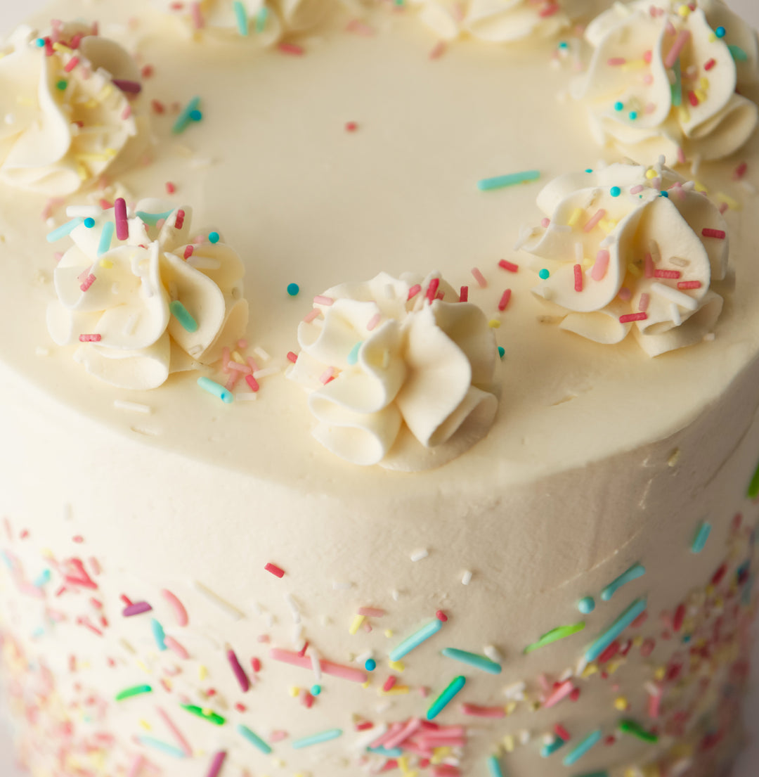 buttercream rosettes and colourful sprinkles on vanilla sponge cake